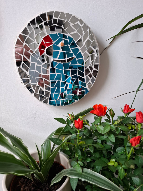 Parakeet mosaic on the wall surrounded by plants 