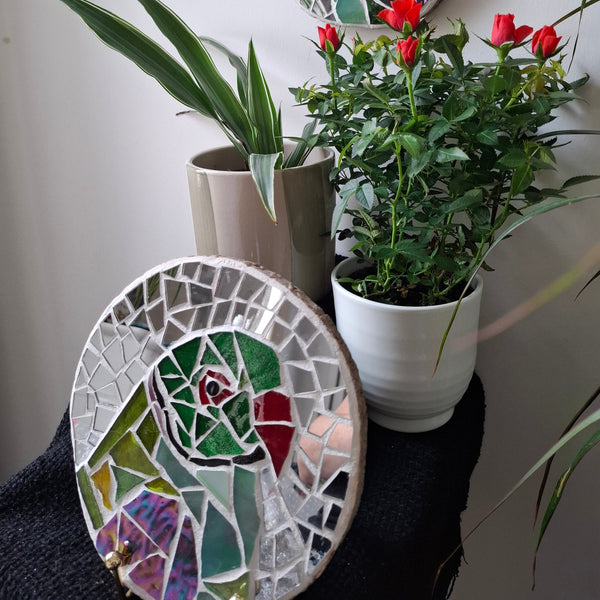 Parakeet mosaic on the wall surrounded by plants 