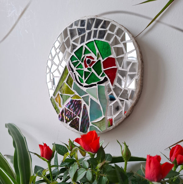 Parakeet mosaic on the wall surrounded by plants 