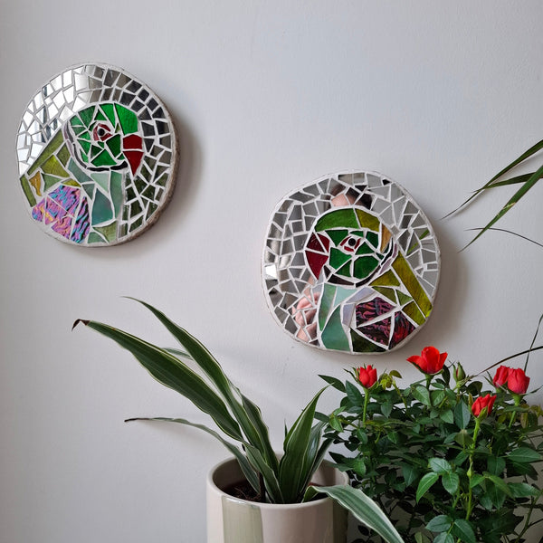 Parakeet mosaics on the wall surrounded by plants 