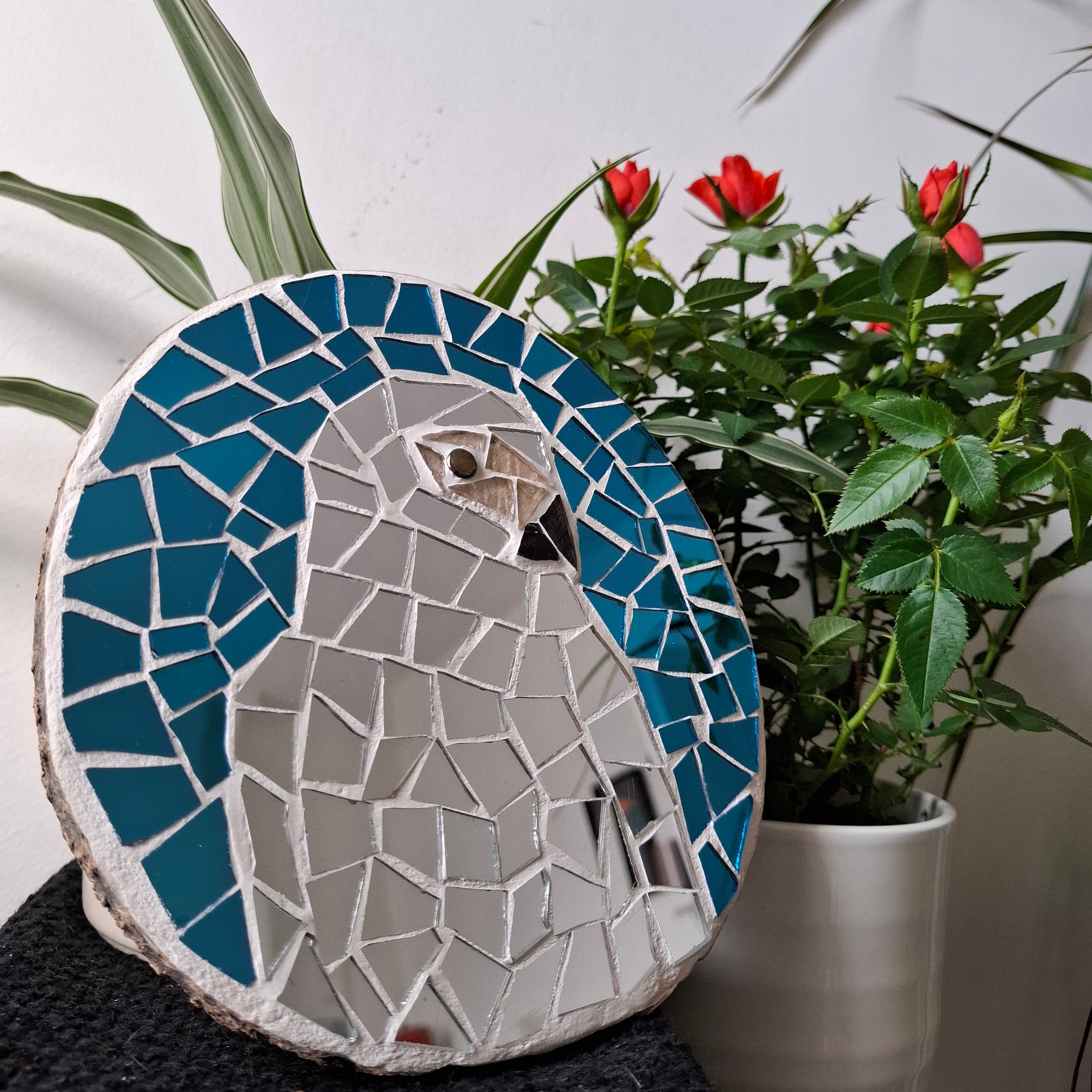Parrot mosaic on the table surrounded by plants 