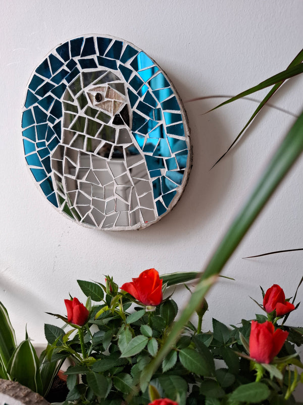 Parrot mosaic on the wall surrounded by plants 
