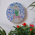 Pigeon mosaic on the wall surrounded by plants
