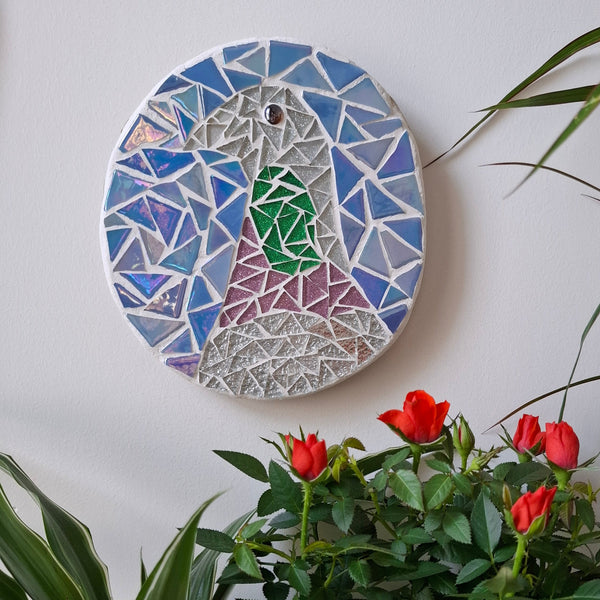 Pigeon mosaic on the wall surrounded by plants
