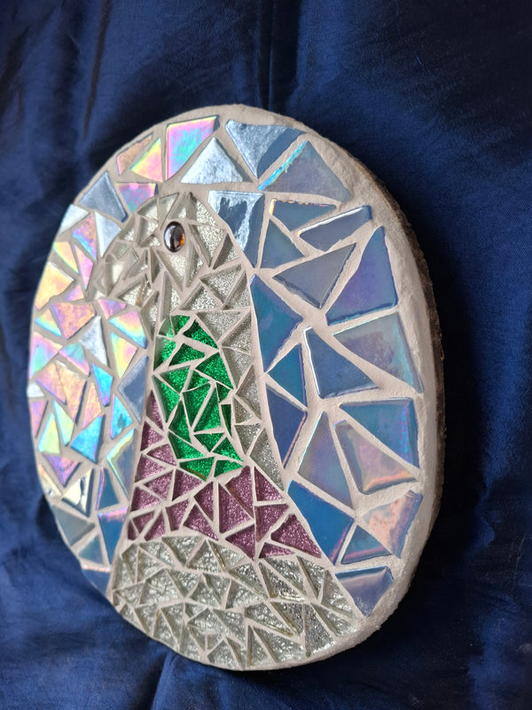 Side view of a circular pigeon mosaic artwork, showing the rustic wood edge.