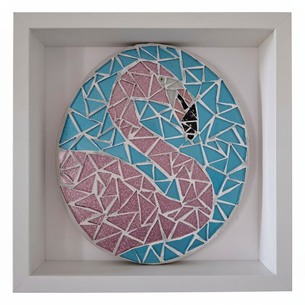 A circular mosaic wall art piece featuring a stylized flamingo design in pink glitter and light blue pieces, mounted inside a white square shadow box.