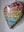 Side view of a heart shaped rainbow mosaic artwork, showing the rustic wood edge.