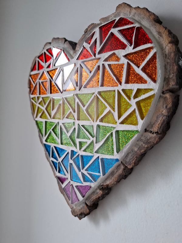Side view of a heart shaped rainbow mosaic artwork, showing the rustic wood edge.