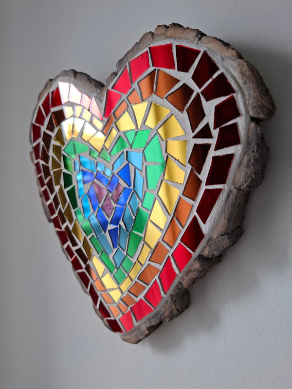 Side view of a heart shaped mosaic art piece with a rainbow pattern.