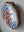 Side view of a circular robin mosaic artwork, showing the rustic wood edge.