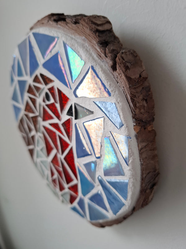 Side view of a circular robin mosaic artwork, showing the rustic wood edge.