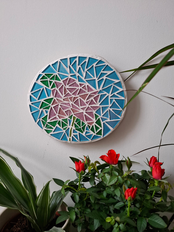 Rose mosaic on the wall surrounded by plants 