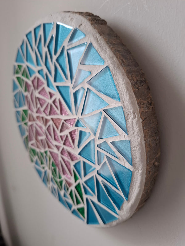 Side view of a circular mosaic rose artwork, showing the rustic wood edge.