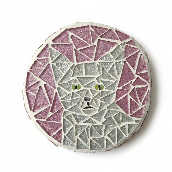 Circular mosaic wall art featuring a stylized cat design. Crafted with glittery silver glass pieces on a sparkly pink background, set on rustic wood.