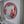 A circular mosaic wall art piece featuring a stylized dog face, made from red and silver glittery triangular tiles with a natural wood edge, mounted on a white frame.
