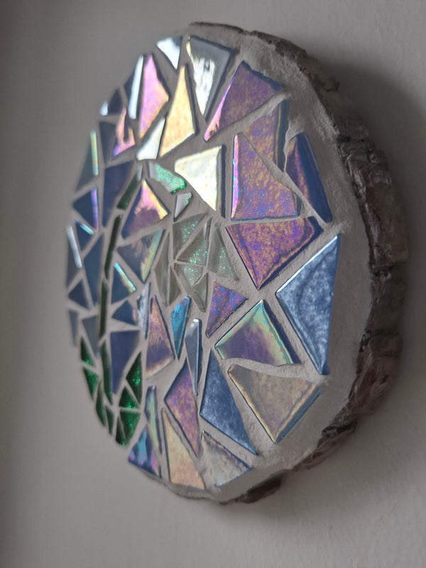 Side view of a circular snowdrop mosaic artwork, showing the rustic wood edge.
