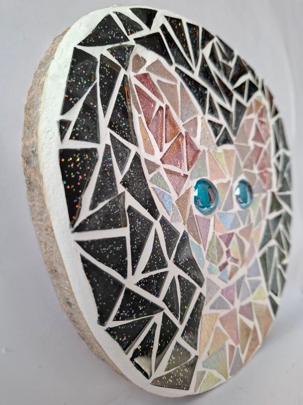 Side view of a circular cat mosaic artwork, showing the rustic wood edge.