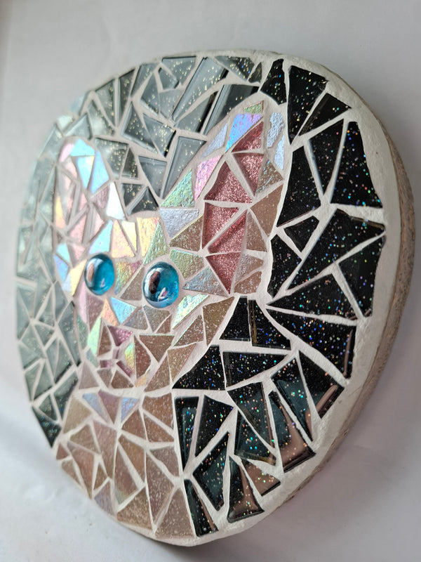 Side view of a circular cat mosaic artwork, showing the rustic wood edge.