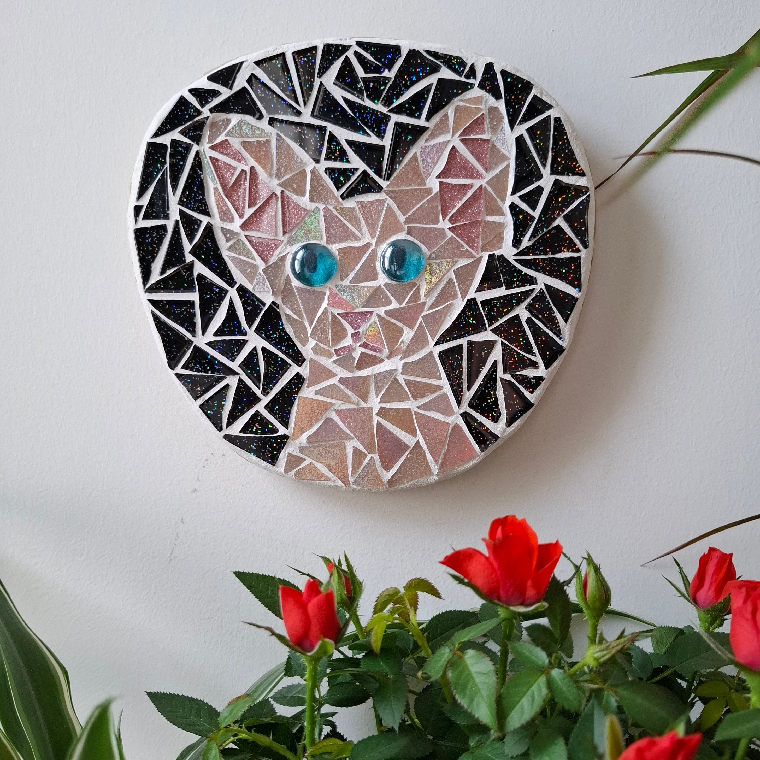 Cat mosaic on the wall surrounded by plants
