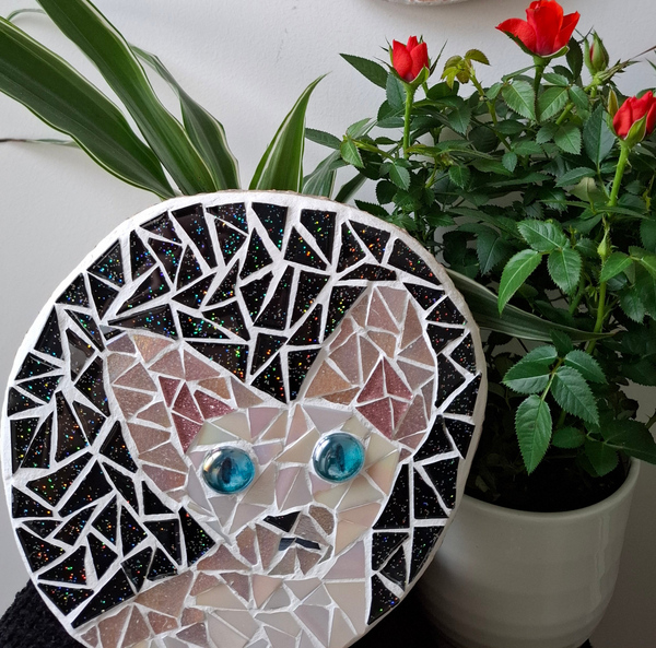 Cat mosaic on the table surrounded by plants
