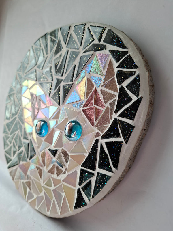 Side view of a circular cat mosaic artwork, showing the rustic wood edge.