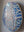 Side view of an oval cat mosaic artwork, showing the rustic wood edge.