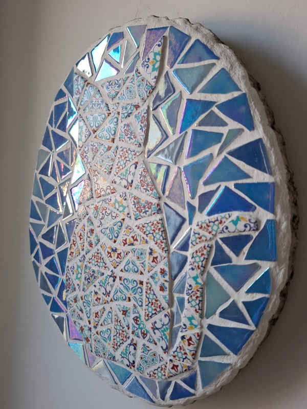 Side view of an oval cat mosaic artwork, showing the rustic wood edge.