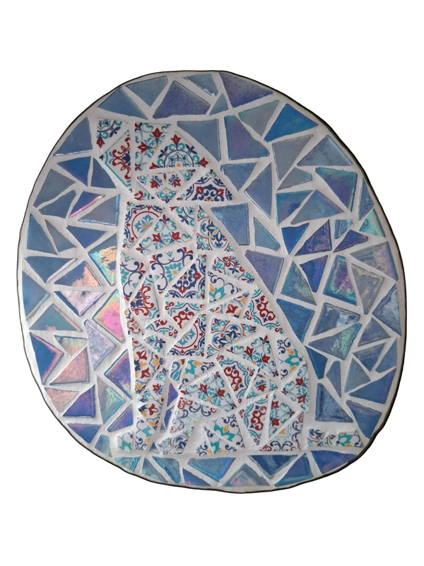 Oval mosaic wall art featuring a stylized dog silhouette design. Crafted with colourful Moroccan patterned ceramic tiles on an iridescent blue background, set on rustic wood. 