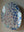 Side view of an oval dog mosaic artwork, showing the rustic wood edge.