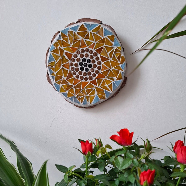 Sunflower mosaic on the wall surrounded by plants
