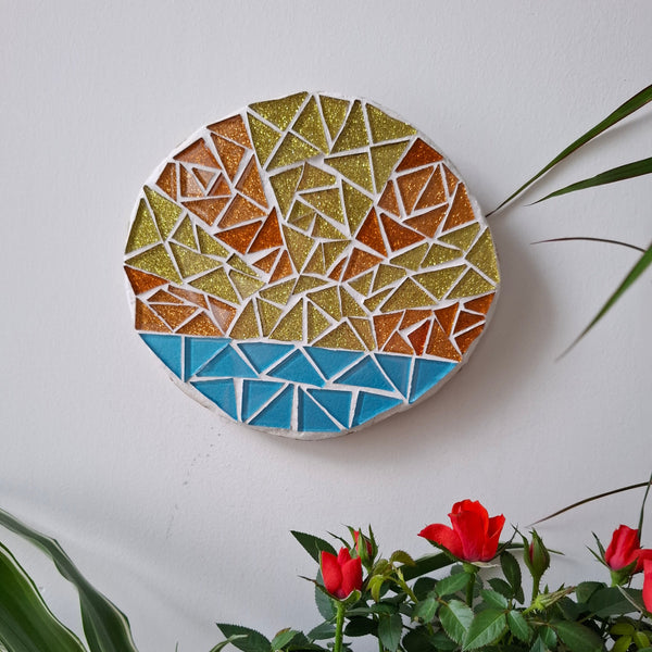 Sunrise mosaic on the wall surrounded by plants
