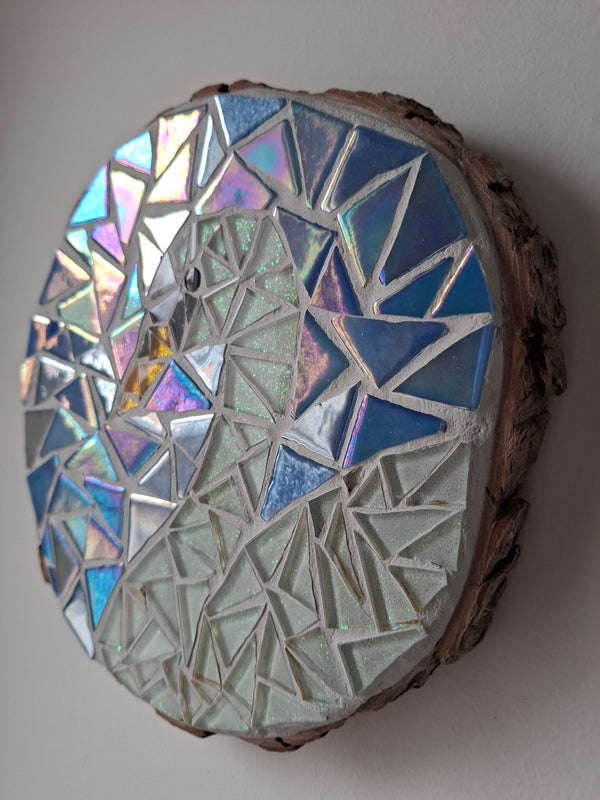Side view of a circular swan mosaic artwork, showing the rustic wood edge.