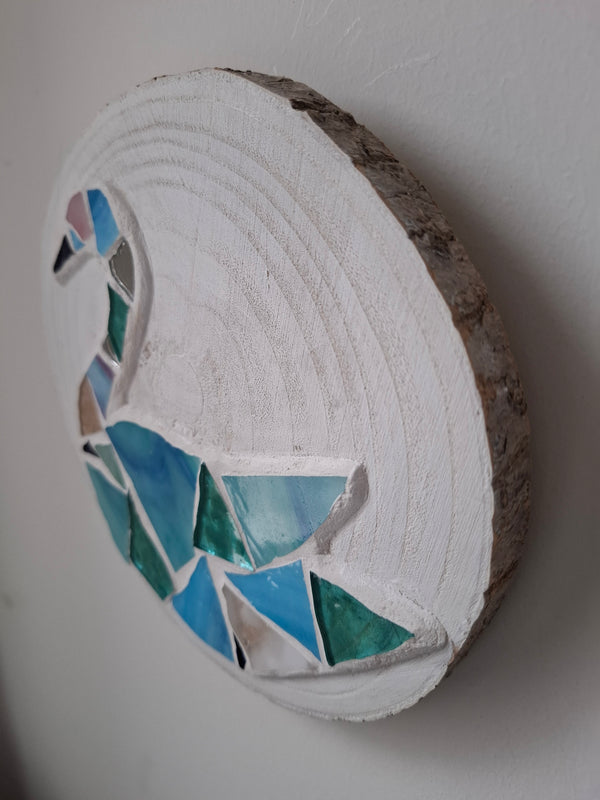 Side view of a circular mosaic swa  artwork, showing the rustic wood edge.