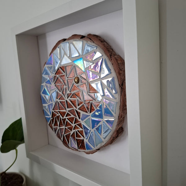 A circular mosaic wall art piece mounted inside a frame. The artwork features a brown dog on a blue background.