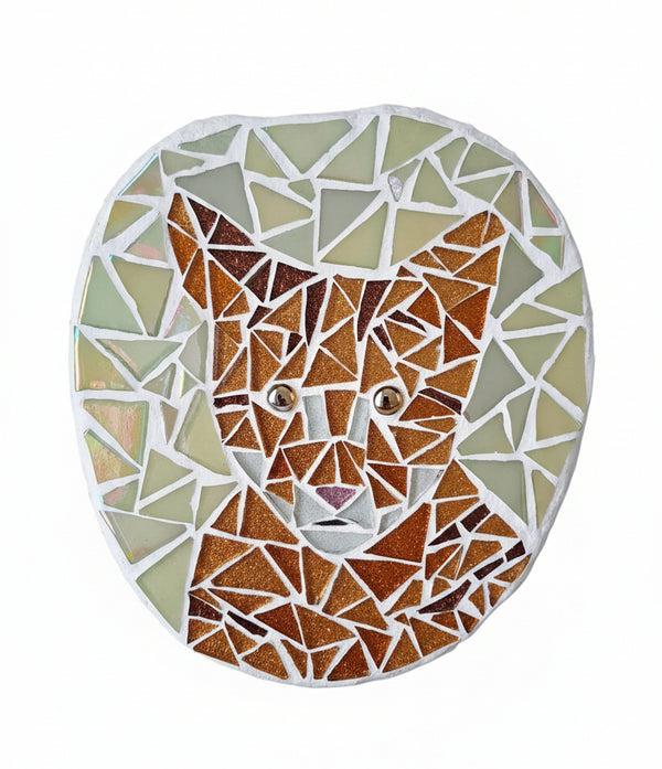 Circular mosaic wall art featuring a stylized cat design. Crafted with glittery gold and bronze glass pieces on an iridescent green background, set on rustic wood.