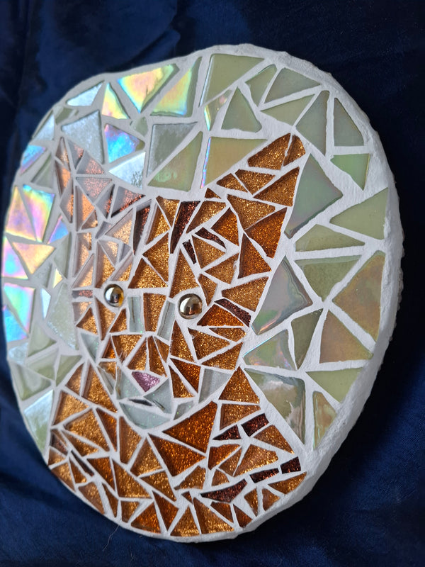 Side view of a circular cat mosaic artwork, showing the rustic wood edge.