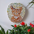 Cat mosaic on the wall surrounded by plants
