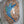 A circular mosaic wall art piece mounted inside a white recessed shelf. The design features a hummingbird in blue, green, and purple tiles separated by white grout lines, with a glossy reflective center.