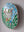 Side view of a oval frog mosaic artwork, showing the rustic wood edge.