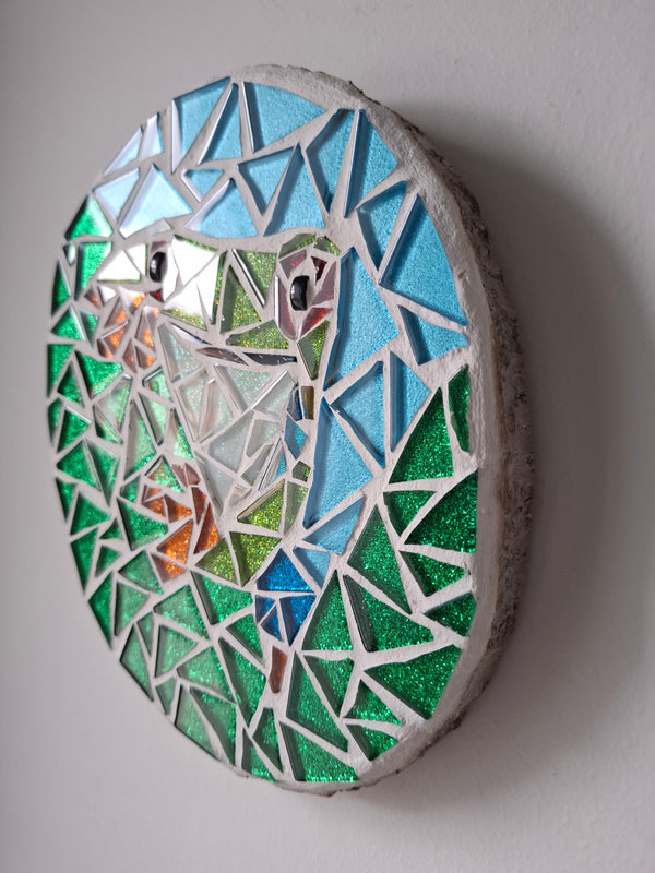 Side view of a oval frog mosaic artwork, showing the rustic wood edge.