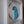 A circular mosaic wall art piece featuring a stylized bird design in blue, red, black, and white, mounted inside a white recessed wall frame.