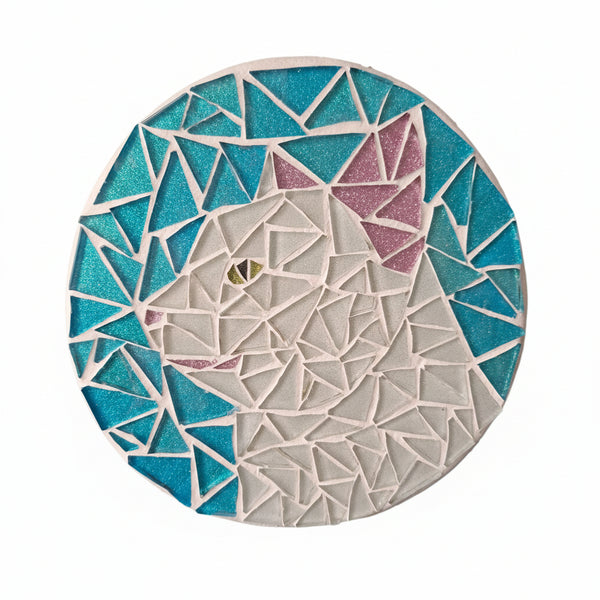 Circular mosaic wall art featuring a stylized cat design. Crafted with glittery pink and white glass pieces on a sparkly blue background, set on rustic wood.