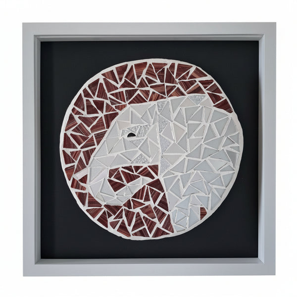 A square framed mosaic wall art piece featuring a stylized elephant in white,  silver and reddish-brown geometric tiles on a dark background, mounted on a light wall.