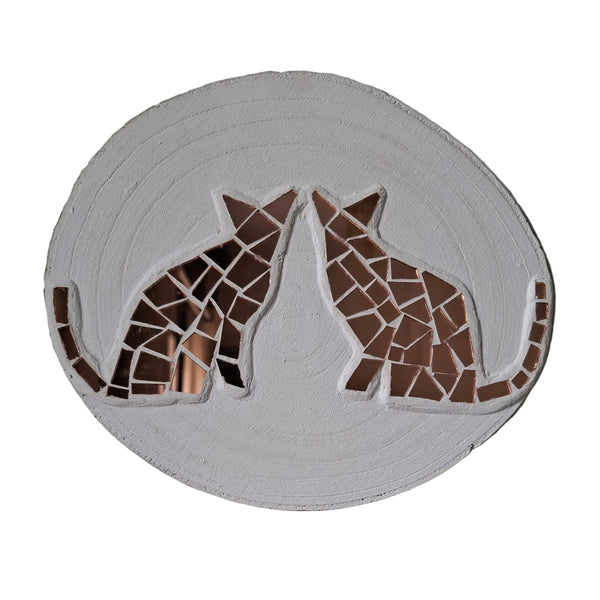 Circular mosaic wall art featuring two stylized cat silhouettes design. Crafted with reflective rose gold mirror glass pieces on a painted white background, set on rustic wood.