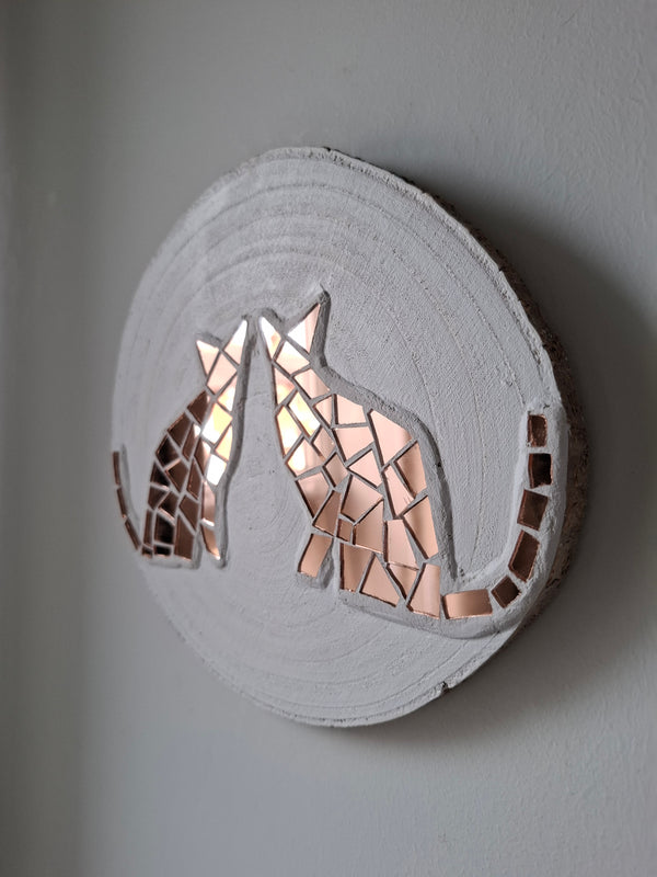 Side view of a circular cat silhouette mosaic artwork, showing the rustic wood edge.