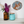A styled interior scene with a white shelf holding an amber glass vase filled with purple and white flowers, a turquoise glass jar with a cork lid, and a round fox mosaic wall art piece above on a white wall.